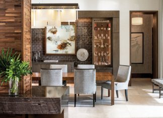 A mix of materials shape the dining room, where The Necessity of the Pause by artist Audrey Phillips hangs on a wall of glazed-ceramic dimensional tile designed by Robert A.M. Stern for Walker Zanger. Taylor King dining room chairs covered in Weitzner’s viscose chenille surround Century’s solid walnut dining table. The light fixture is a custom design by Shakúff, a Brooklyn-based studio known for blown- and fused-glass lighting.