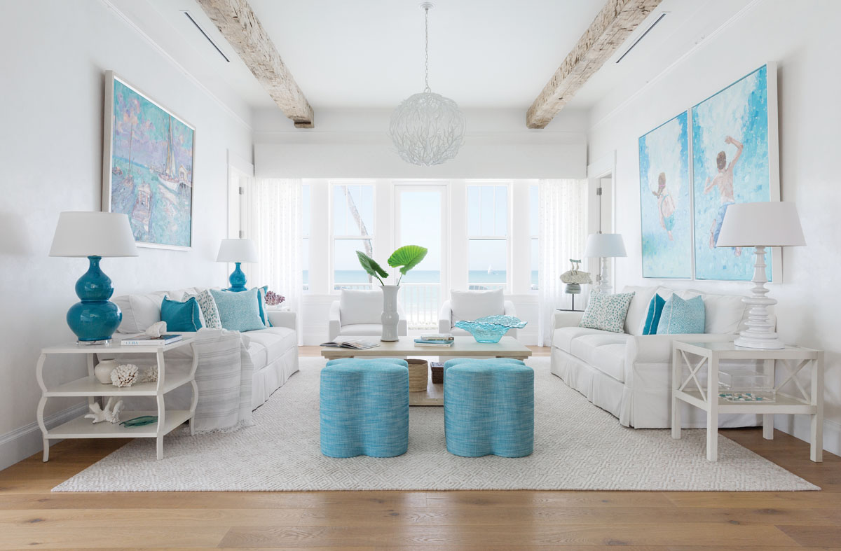 The living room is on the second floor of the cottage. Upholstered chairs in front of the windows swivel to take advantage of the endless blue views. Paintings by Floridian artists float above a matched pair of sofas: a sailboat scene by James Kerr of Delray Beach, and a pair of swimming children by Jacksonville artist Eileen Corse.