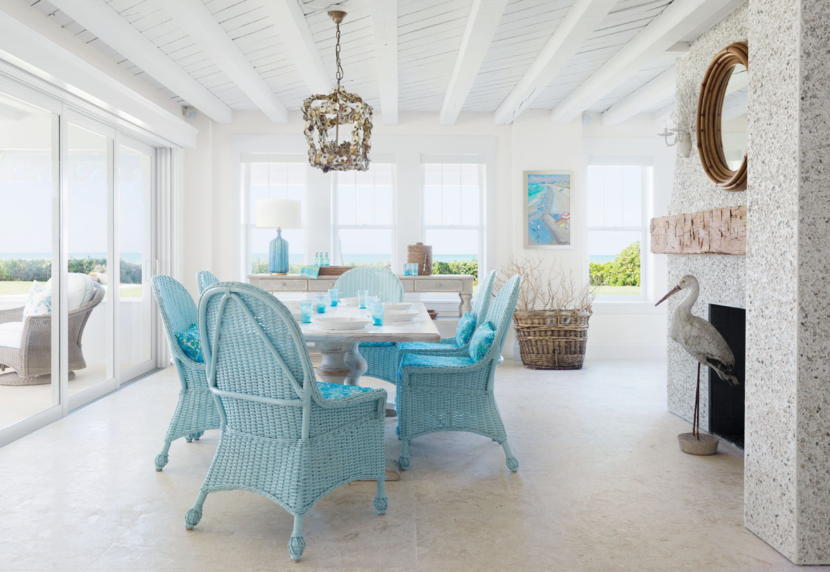 On the first floor, the dining area showcases the cottage&rsquo;s original fireplace made of tabby&mdash; a mixture of concrete and crushed shells. The owners added the mantle, which interior designer Jett Thompson says gives the look of driftwood. The space can be connected to the patio, thanks to sliding glass doors that fold all the way back to create &ldquo;one great big, glorious room,&rdquo; says Thompson.