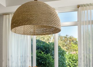 The dining room table with its tree trunk base and fossilized clamshell top is an elegant counterpoint to the woven sea grass dome fixture that hangs above.