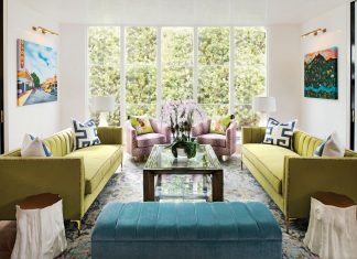 Happy Hues Bring the Flair in Winter Park Home The expansive windows in the living room look out onto a fountain. The tree trunk-inspired end tables are lacquered in white, with tops painted in gold leaf.