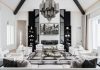 To impart cosmopolitan elegance, the palette in the main living room consists of black, white, and gray. The large chandelier by Terzani drove the design decisions in this part of the home, which features symmetrically paired chairs and a sofa opposite the expanse of the fireplace.