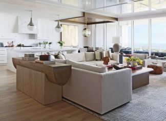 The living room flows effortlessly into a glossy all-white kitchen outfitted in Calacatta Lincoln marble. The design team amplified the clean design by wrapping the stove hood in the same marble for a modern, seamless look, and coloring the pendant lights to match the marble’s gray veining.