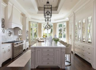 In the kitchen, bespoke lighting fixtures hang over a large gray marble island that anchors the room. Per the homeowners, the space was modernized to satisfy modern lifestyles.