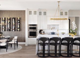 Modern Style Abounds in Dade City Interim Residence Emtek cabinet hardware and an Arteriors fixture over the island accentuate the kitchen’s elegant design. Global Views barstools bring a sleek black finish to the space. A Phillip Jeffries wallcovering backdrops the dining room’s dynamic wine wall.