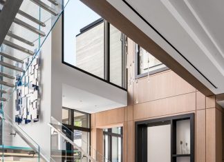 The residence’s glass staircase is seamlessly integrated into the foyer. Designed by Flora Di Menna, it is a major focal point throughout the main living spaces. The custom-designed cabinetry inset into the wall serves as a niche for sculpture and echoes the tones and lines of the metal grids on the entry door.