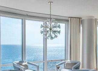 A seating area for drinks and conversation seems to float over the sparking gulf waters. Pale blue velvet swivel chairs from Century Furniture pair with round bone accent tables from Made Goods. A crystalline coral-inspired chandelier from John-Richard elevates the organic vibe.