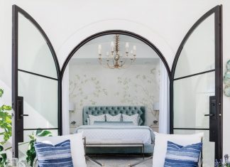 Gainesville Home Evokes European Country Charm Framed by arched glass doors opening to the pool area, the primary bedroom illustrates artful symmetry. A hand-painted prairie landscape mural by Rick Chance creates a graceful backdrop for Anthropologie’s velvet tufted headboard and Gabby nightstands.
