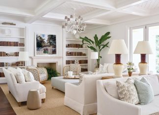 Earth-toned upholstery was chosen for the sofas and chairs in the living room. The custom bookshelves are filled with color-blocked volumes. The duo of lamps is from Paul Schneider Ceramics and the chandelier is from Neirmann Weeks.