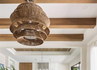 Inside a Collected and Curated Family Home on the Manatee River The living room’s soaring height demanded an overscale light fixture with a woven finish that adds to the resort-like ambience. Immediately noticeable are the white oak beams on the ceiling, which bring a sense of warmth to the room. Neutral furnishings below keep the room’s textures balanced.