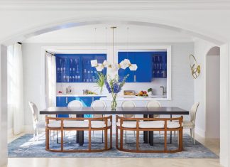 Art and Vibrant Colors Speak Volumes in Gulf Stream Home A view of the dining room and kitchen reveals the bold blue cabinetry that the homeowners insisted on at their first meeting with the design team. “It’s a high-gloss lacquer finish, which really makes the blue color pop,” says McCauley. “Since the kitchen is visible from the living room, we knew it would become a focal point.” The centerpiece of the dining area is a light pendant by Gabriel Scott.