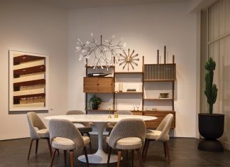 A mid-century modern dining room setup from DWR featuring the Saarinen oval dining table, Saarinen chairs, the Royal Systems wall unit by Poul Cadovius, and the Heracleum III Suspended light fixture by Bertjan Pot for Moooi. Photo courtesy of Design Within Reach