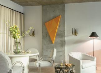 Inside a Designer’s Own West Palm Beach Condo In the condo’s dining area, chairs designed by Leon Rosen for Pace Furniture in the 1970s introduce a refined sense of heritage with their arched backs and Lucite arms, which quietly echo a Roman arch motif. The orange triangular painting on the exposed concrete wall was created by designer Paul Sherrill’s business partner, José Solis Betancourt, who gifted it to him as a housewarming present. “When I saw it in his studio, I knew it was the one piece that would add an unexpected touch to the room,” says Sherrill.
