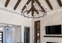 Soaring vaulted ceilings and a luminous chandelier from Wilson Lighting infuse grandeur into the great room, punctuated with a fireplace wall clad in continuous-vein porcelain slabs. Texture-rich furnishings include a Massoud sofa, Lexington armchairs, swivel chairs and cubes from Sherrill Furniture, and a leather ottoman from Wesley Hall.