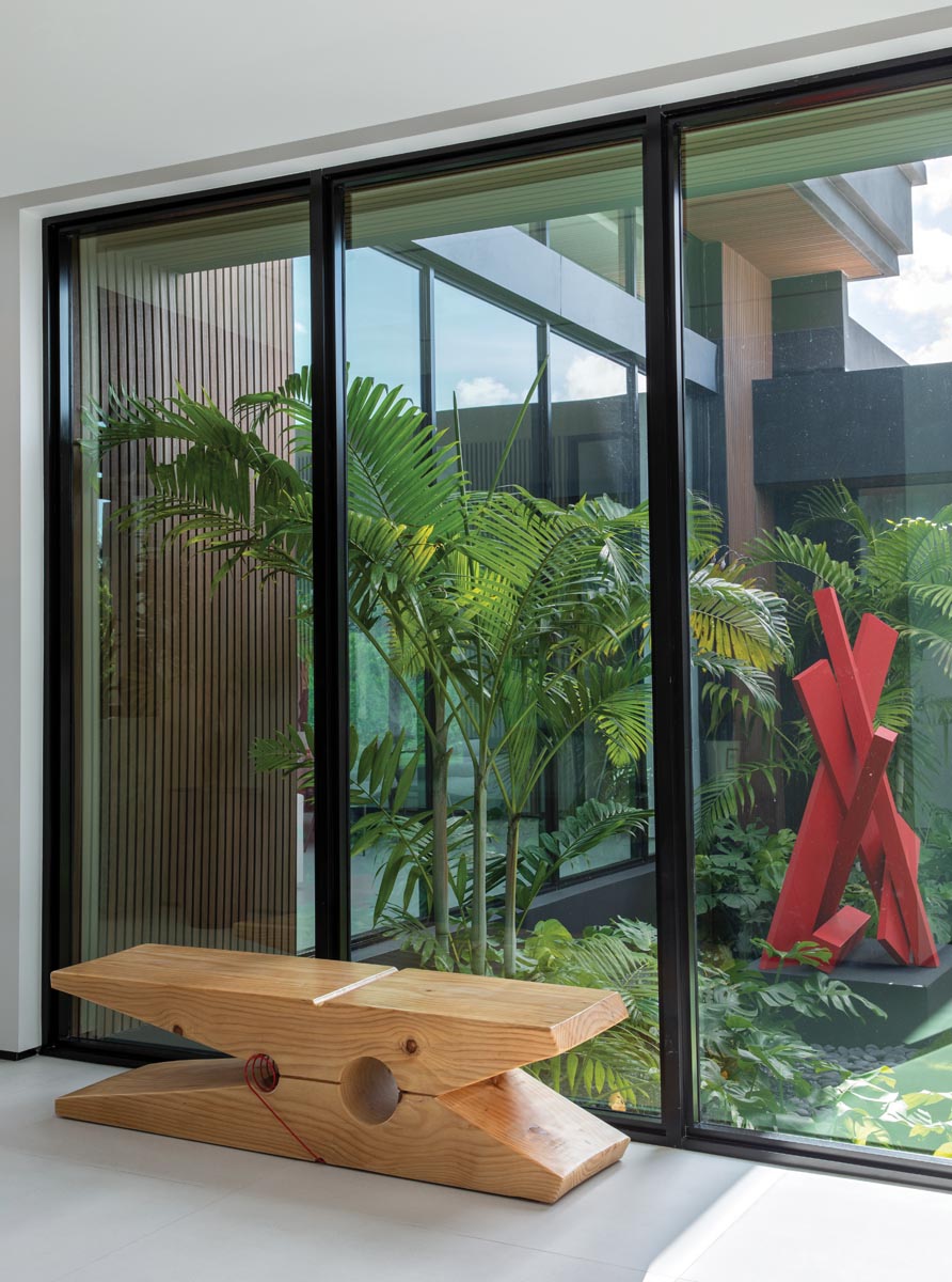The homeowners&rsquo; collection of art and fine design includes a red metal sculpture (showcased among palms in the garden) and a clothespin-inspired bench.