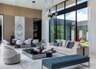A Case for Contemporary in Olympia Heights The living area’s double-height ceilings and expansive glass openings create a dynamic visual connection to the landscape. Anchored by a streamlined RH sofa paired with sculptural swivel chairs from Harmony Luxury Furniture, the space is crowned by an elegant crystal Lens chandelier from Bomma. The adjacent dining room complements the aesthetic with mesh pendant chandeliers from Luceplan and a Luxor dining table by Rodolfo Dordoni.