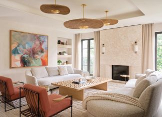 Palm Beach Home Reimagines Historic Coastal Style The living room features a coral stone fireplace accented with fine fluting at the lower portion for textural appeal. Built-in shelves flank the artwork centered behind a Poltrona Frau sofa. The abstract painting inspired the subtle orange hues of a pair of Avenue Road lounge chairs and the gold-finished rattan pendants by Hudson Valley Lighting.