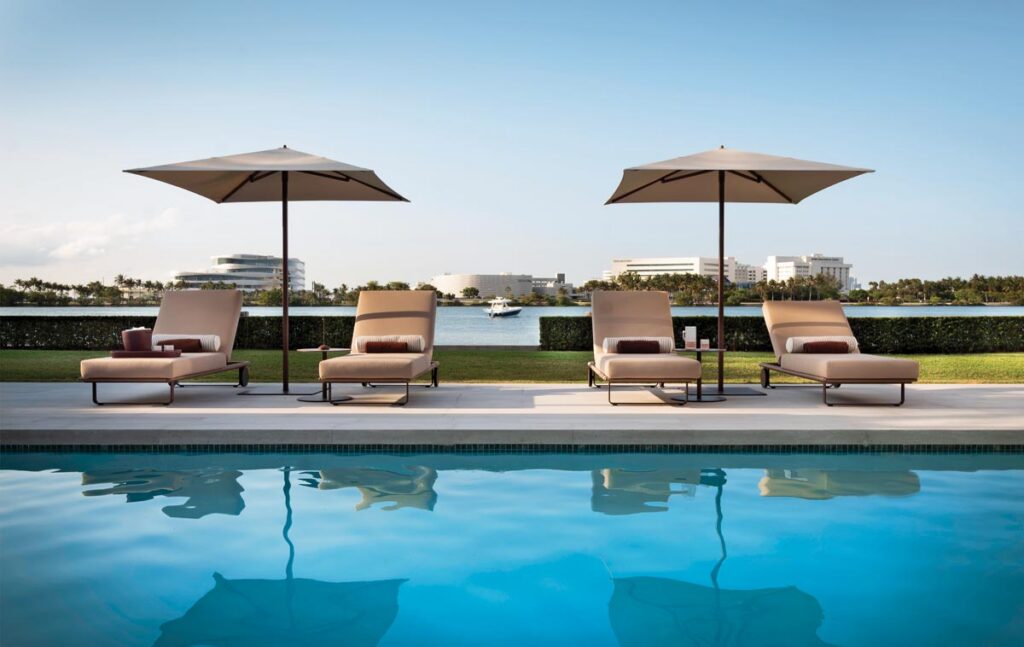 Kettal poolside loungers and umbrellas line the pool patio against the Biscayne Bay backdrop