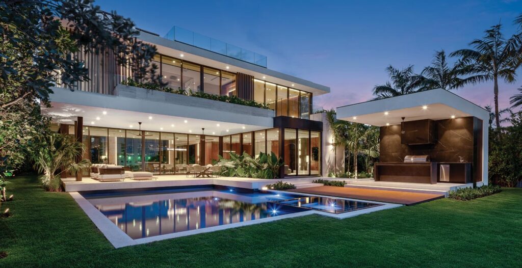 A broad covered terrace, outfitted with clean-lined Minotti furnishings, features an adjacent kitchen pavilion. Lush tropical plantings wrap the garden edges, creating full privacy while rooting the house firmly in the landscape.