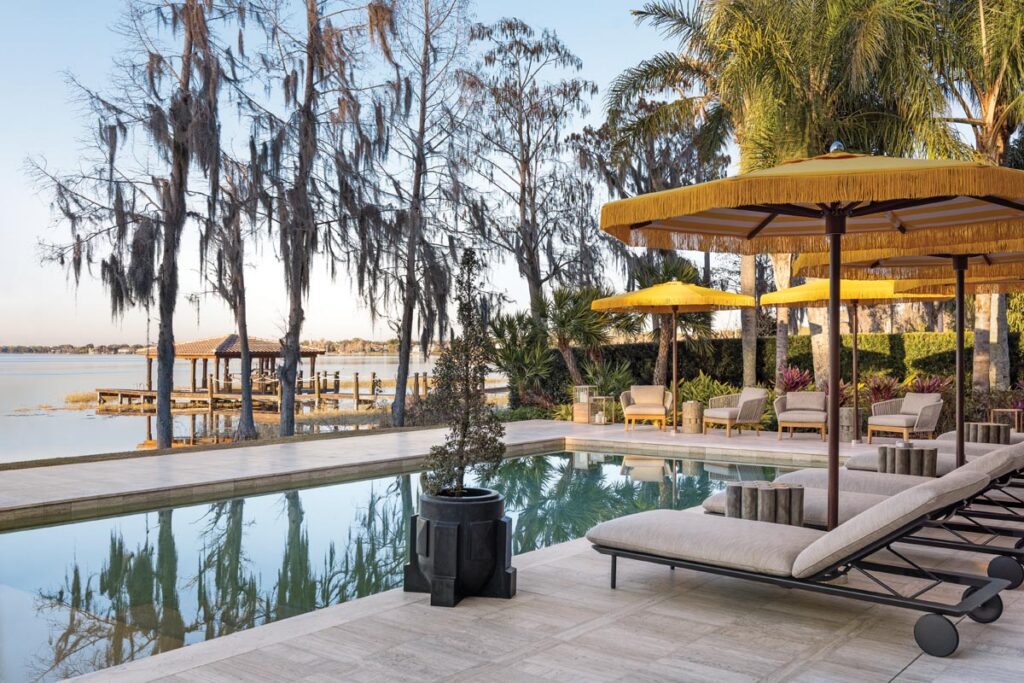 Around the pool, yellow Ocean Master Max parasols by Tuuci provide shade for the Tribù Senja loungers as well as bright color to the overall backyard scene