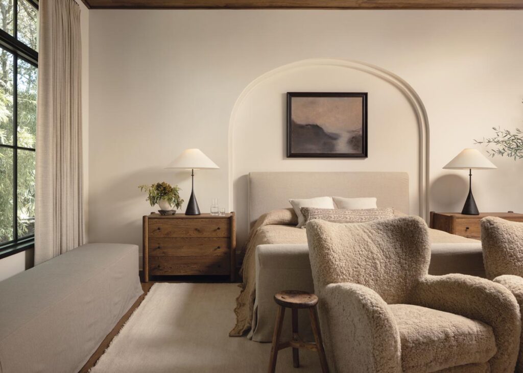 The primary bedroom brings together linen, bouclé, wood, wool, and softly layered bedding. Because the palette is restrained, the contrast between these textures provides much of the room’s depth and warmth.
