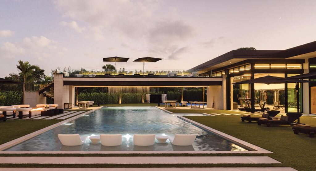 Across the pool, an observation deck commands the courtyard, sending a dramatic rain curtain cascading directly into the water below. The vista opens toward the home’s sprawling wellness wing.