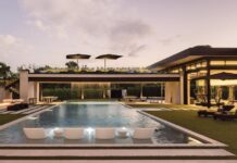 Wellness-Oriented Naples Estate Boasts Five-Star Appeal Across the pool, an observation deck commands the courtyard, sending a dramatic rain curtain cascading directly into the water below. The vista opens toward the home’s sprawling wellness wing.