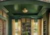 Snell Isle Home Boasts Timeless Flourish A coffered ceiling brings architectural interest to the library, along with built-in shelving that arches over a mint green sofa from Rowe and a custom upholstered ottoman. A Pierre Frey mural wallpaper continues from the hallway, adding a rich layer of pattern.