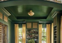 Snell Isle Home Boasts Timeless Flourish A coffered ceiling brings architectural interest to the library, along with built-in shelving that arches over a mint green sofa from Rowe and a custom upholstered ottoman. A Pierre Frey mural wallpaper continues from the hallway, adding a rich layer of pattern.