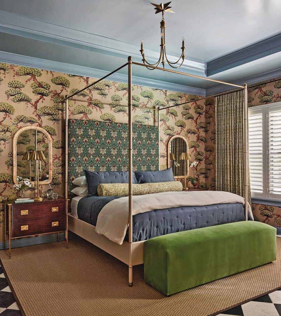 Painted in Farrow & Ball’s soft blue Selvedge, the ceiling defines the primary bedroom above a custom Julian Chichester leather-wrapped four-poster bed capped by a green velvet bench by French & French Interiors. Patterned accents, including an upholstered headboard and a Pierre Frey grasscloth wallpaper, blend in flawlessly.