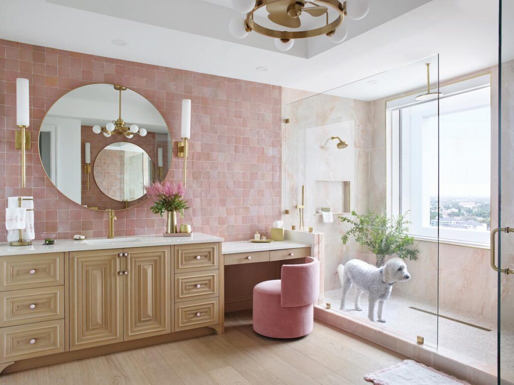 The design team leaned into pink in the primary bathroom with rose mosaics from Artistic Tile on the vanity wall and a matching stool from Chaddock