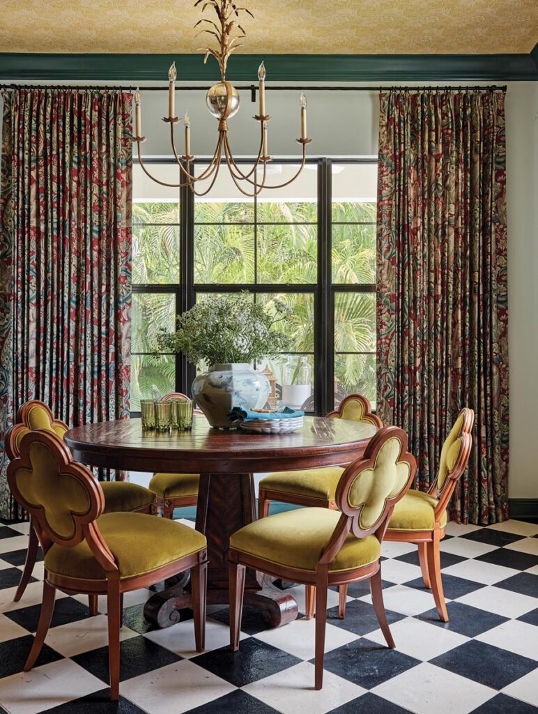 The dining room echoes the living room’s aesthetic with a richly patinaed pedestal table from Theodore Alexander surrounded by Hickory Chair’s chartreuse velvet-covered seating. Patterned draperies from Morris & Co. and a chandelier from Visual Comfort polish the look.