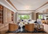 Easy Elegance in Contemporary Moorings Home Designed to feel luxurious without becoming grandiose, the great room layers a Vanguard Furniture sectional with Wildwood & Chelsea House lamps, an Arteriors accent table, and Universal Furniture lounge chairs and side tables. Window treatments from L. Benedetti Draperies and custom EDGE cabinetry complete the textured setting.