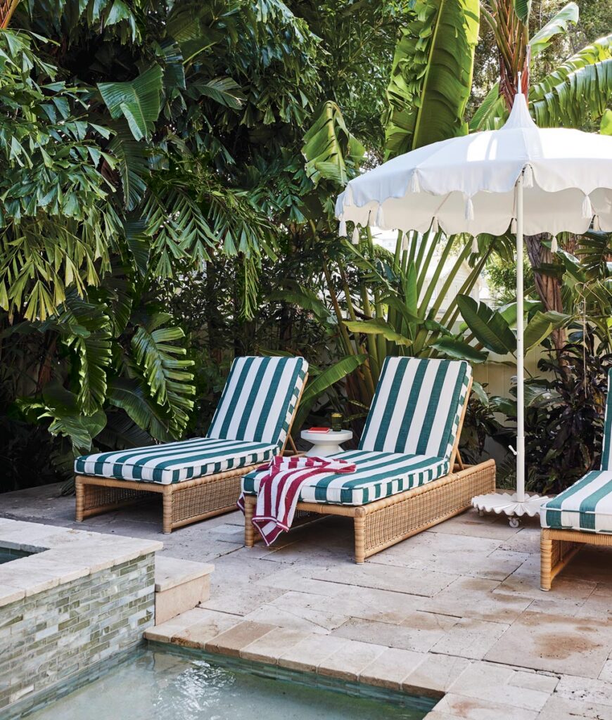 Tropical landscaping brings an added layer of privacy to this Mediterranean and Spanish–influenced home. Lined with the homeowners’ vintage-inspired wicker loungers sheltered under a white umbrella, the pool patio is relaxing and charming.