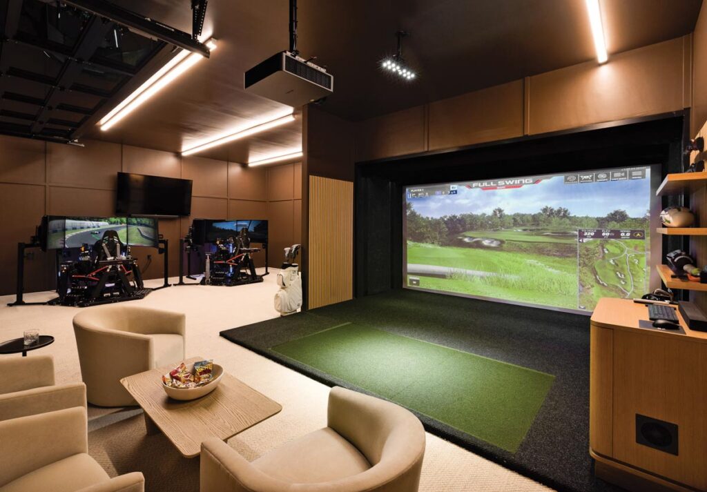 Two professional-grade racing simulators share space with a full-wall golf simulator in the game room